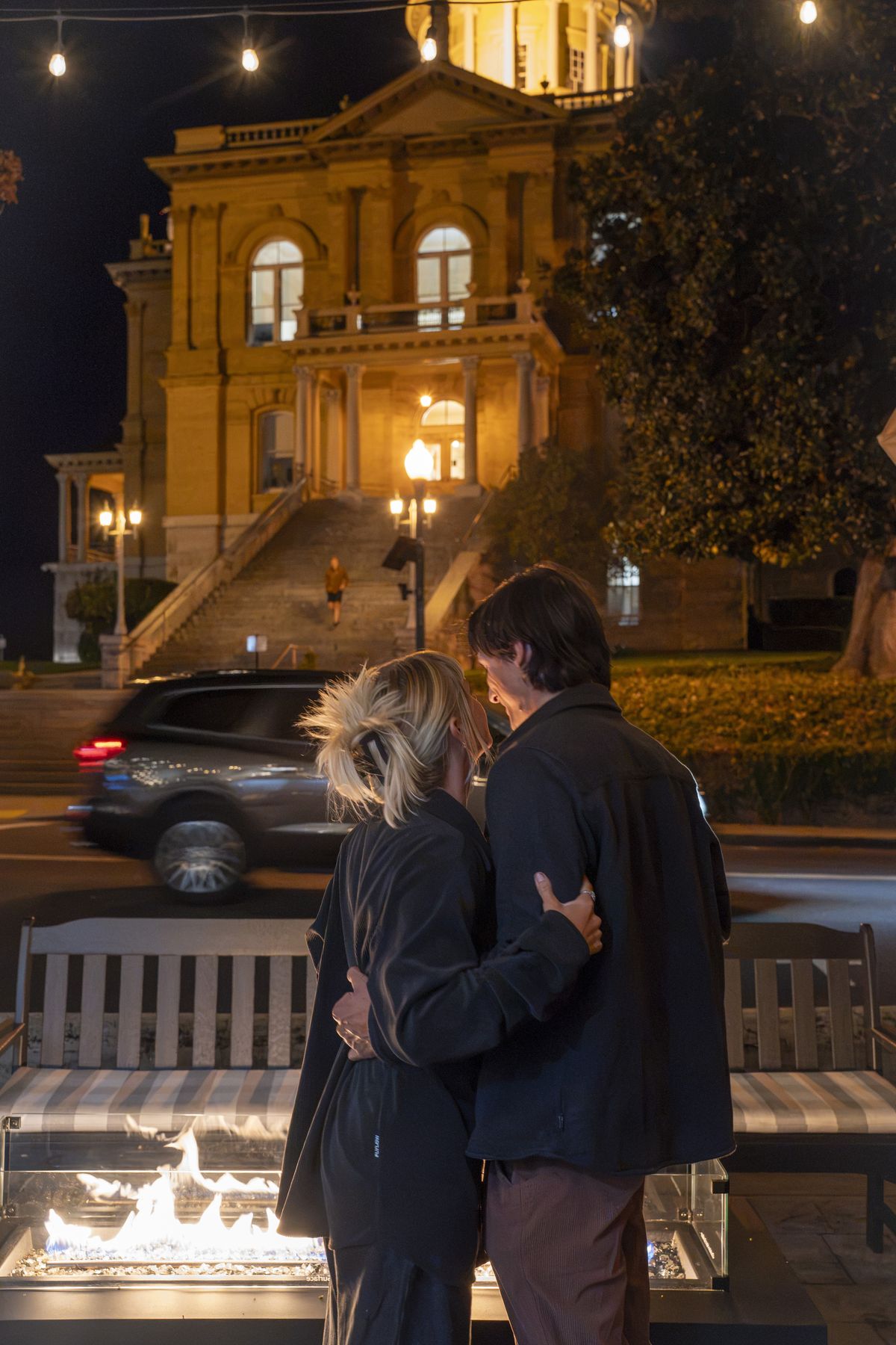 A couple by the fire, the historic courthouse lit up behind them