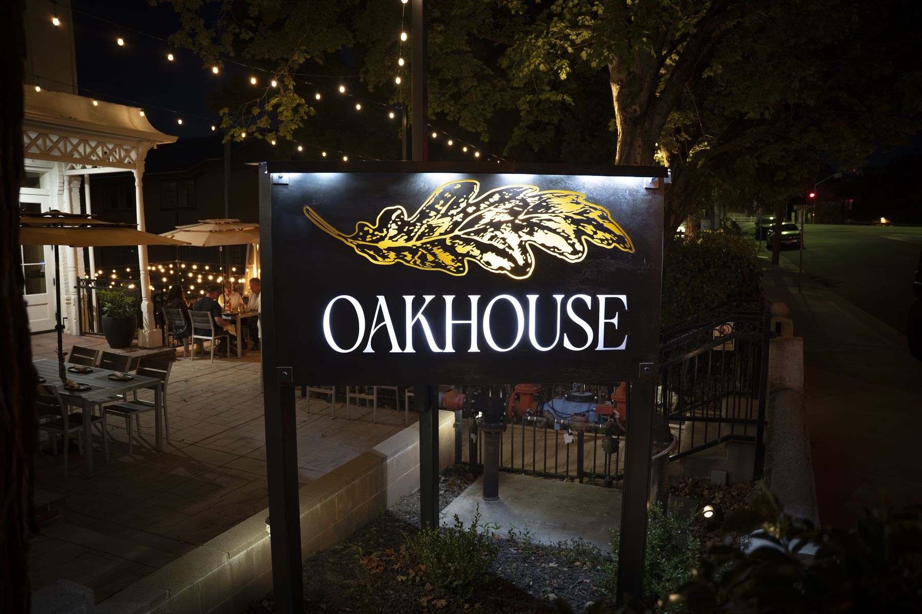 The Oakhouse sign lit up over the patio at night